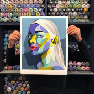 Artiste Alber tenant un print street art dans son atelier de Bordeaux