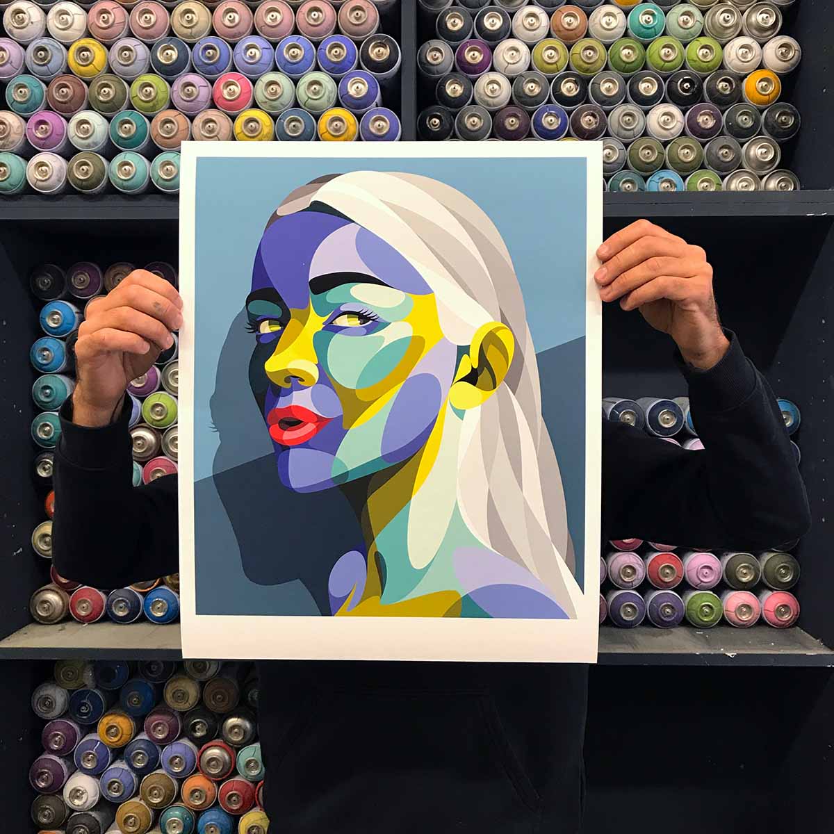 Artiste Alber tenant un print street art dans son atelier de Bordeaux